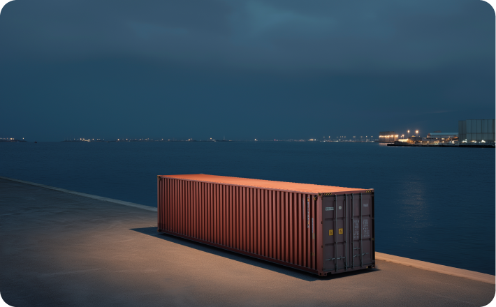 Shipping container on a concrete pier at night, harbor lights in the distance